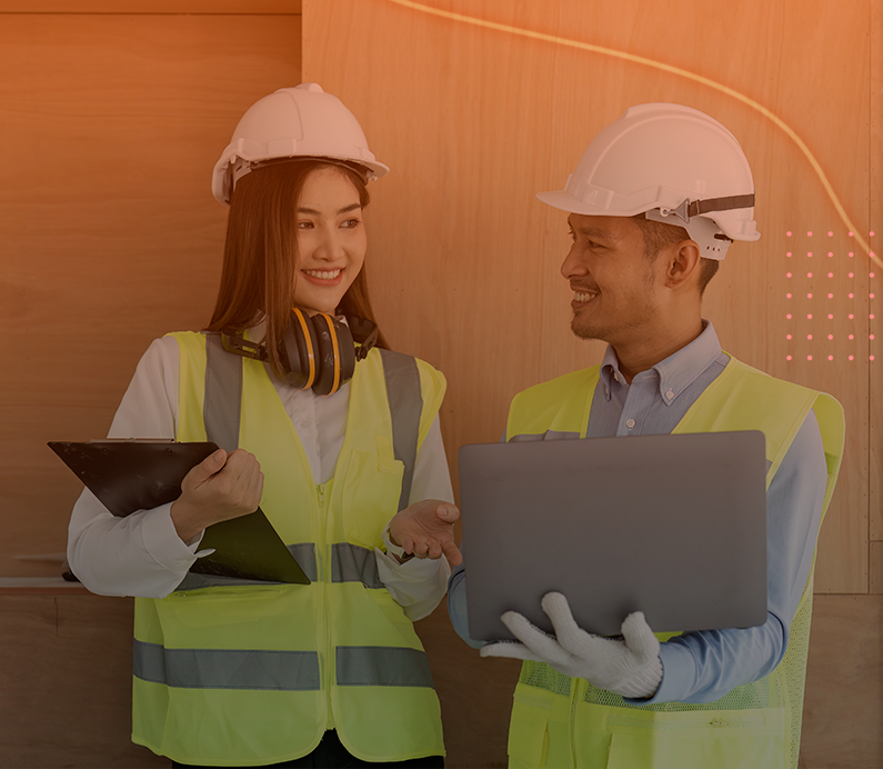 Mulher e Homem sorrindo, vestem coletes e capacetes de segurança, olhando para tablets e computador nas mãos. Banner para ilustrar a página do Engeman Lite do Software Engeman.